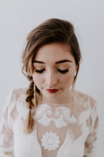 Panna Młoda prezentująca swój ślubny make-up w warkoczu i białej sukni z haftem