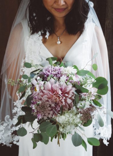 Panna Młoda trzymająca duży, rustykalny bukiet ślubny w odcieniach fioletu