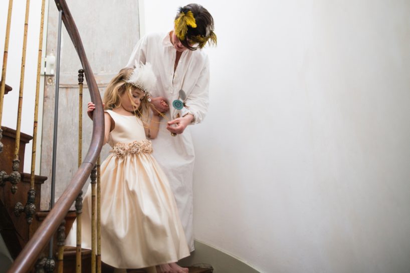 Dziewczynka schodząca po schodach w eleganckiej sukni trzymająca za rękę swoją mamę