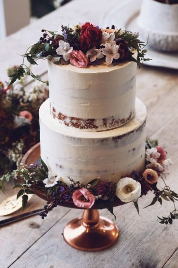 Dwupiętrowy jasny tort ślubny, naked cake, zdobiony bordowymi, różowymi i białymi kwiatami.