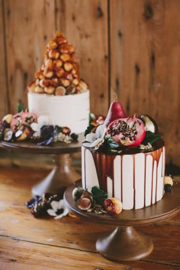 Dwa jasne torty ślubne na paterach, bogato zdobione figami i czekoladowymi polewami