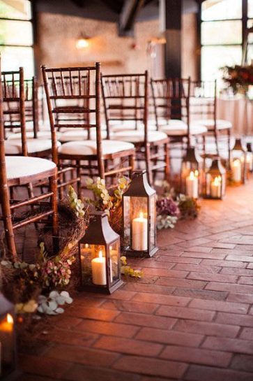 Lampiony ślubne z kwiatową aranżacją, w tle drewniane , ślubne krzesła.